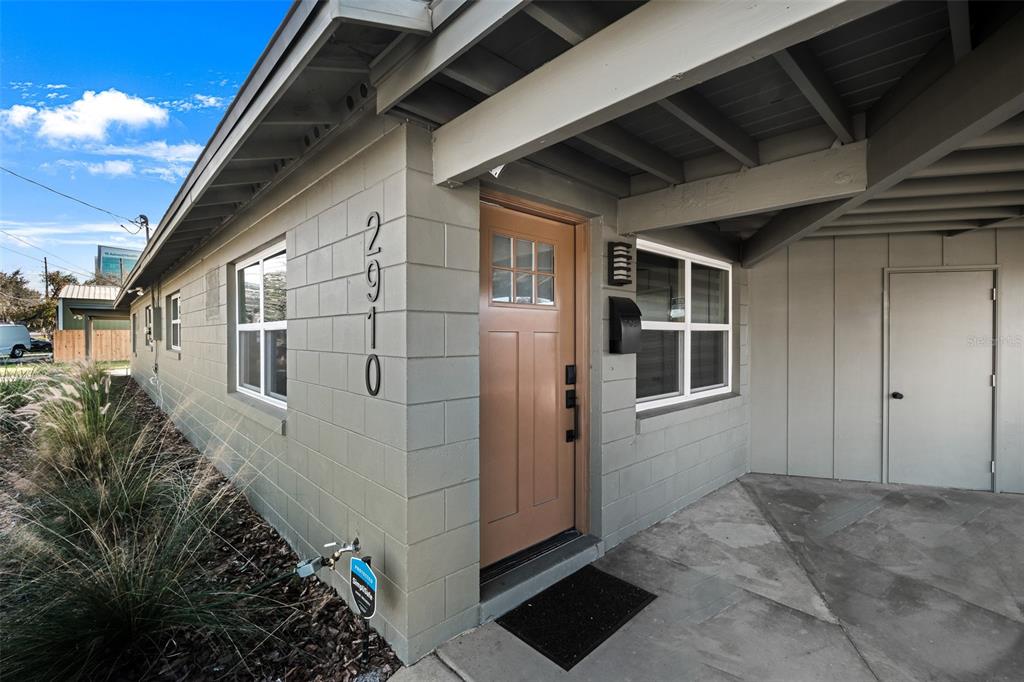 A tan front door with a small window sits next to a concrete block wall — 2910 DADE AVENUE, ORLANDO, FL