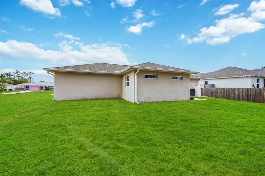 The exterior of a beige, single-story house with a grassy backyard and a wooden fence — 2260 MISTLETO LANE, NORTH PORT, FL