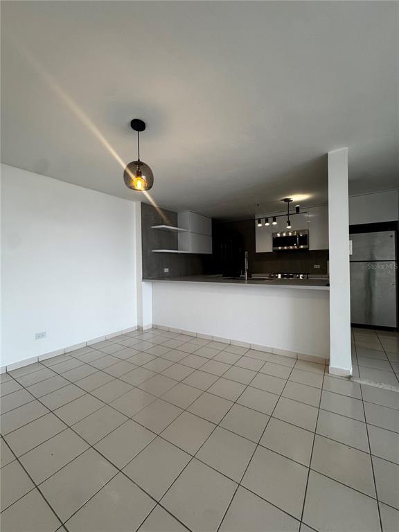 A kitchen with white cabinets and a breakfast bar overlooks a tiled dining area — 650 CUEVAS BUSTAMANTE COND. SEGOVIA UNIT 15, SAN JUAN, PR