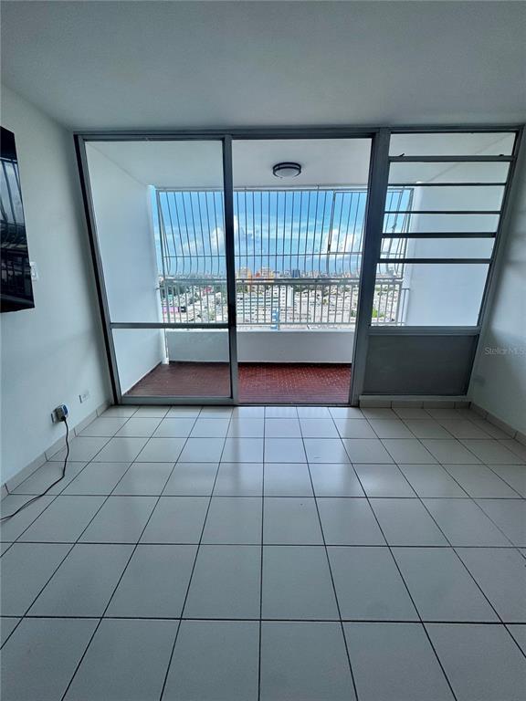 A room with white tile flooring features a large sliding glass door opening onto a balcony — 650 CUEVAS BUSTAMANTE COND. SEGOVIA UNIT 15, SAN JUAN, PR
