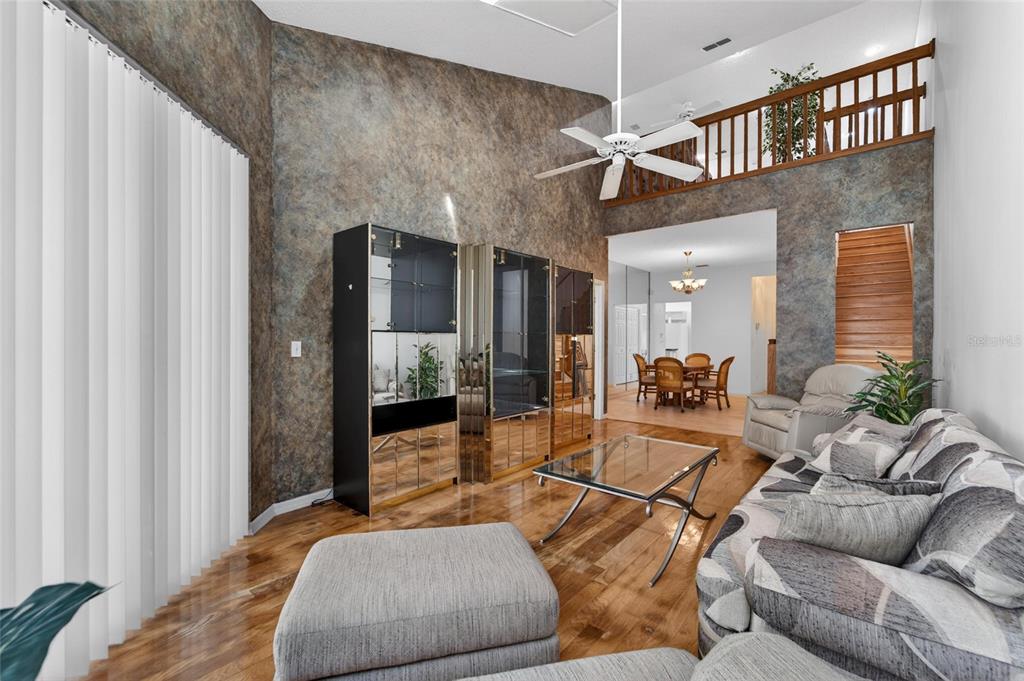 A living room features a vaulted ceiling, textured walls, hardwood floors, and a loft balcony — 1050 STARKEY ROAD UNIT 509, LARGO, FL