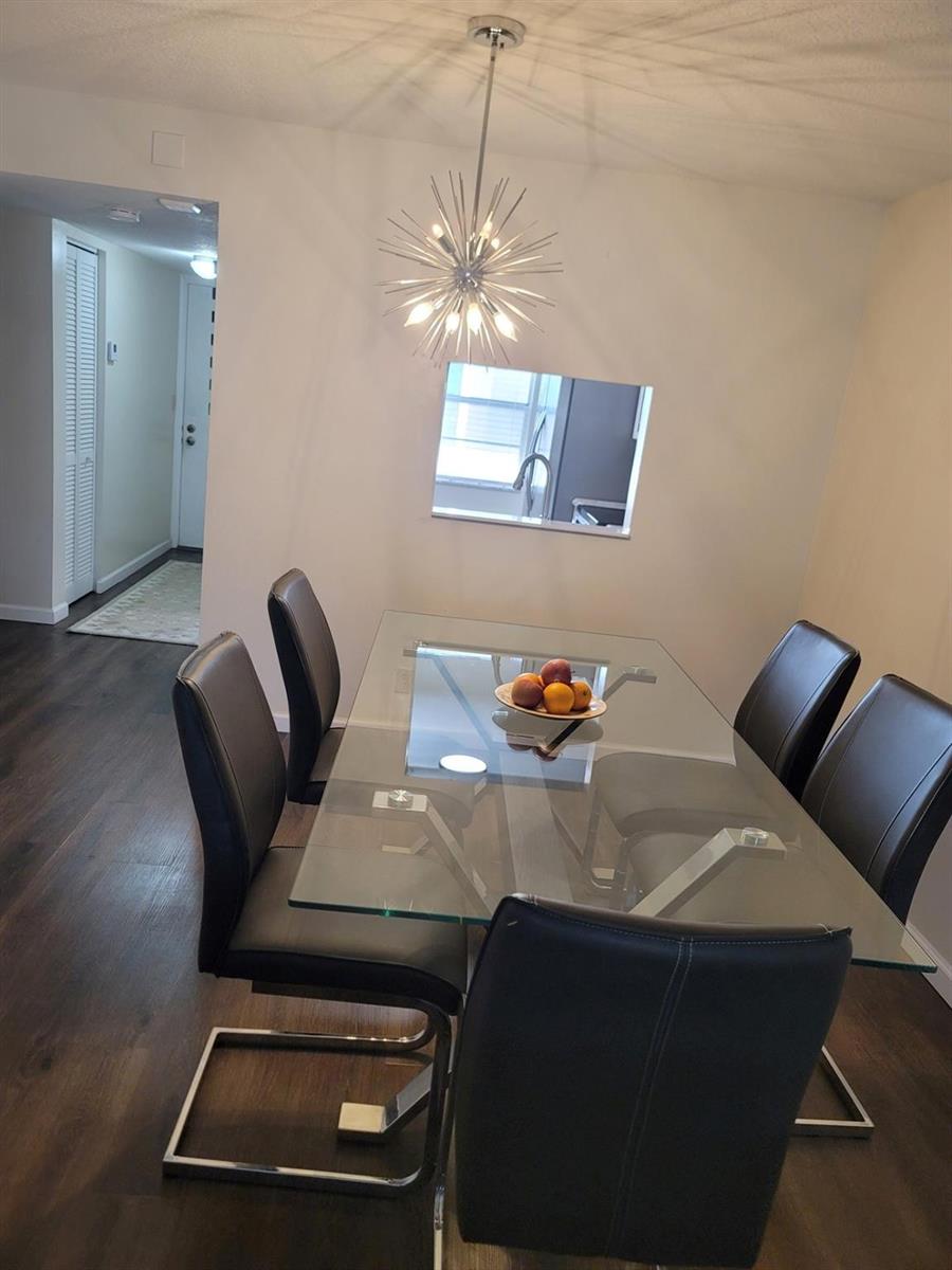 A dining room features a glass-topped table, six leather chairs, and a starburst chandelier — 3774 Inverrary Boulevard # P202, Lauderhill FL 33319, LAUDERHILL, FL