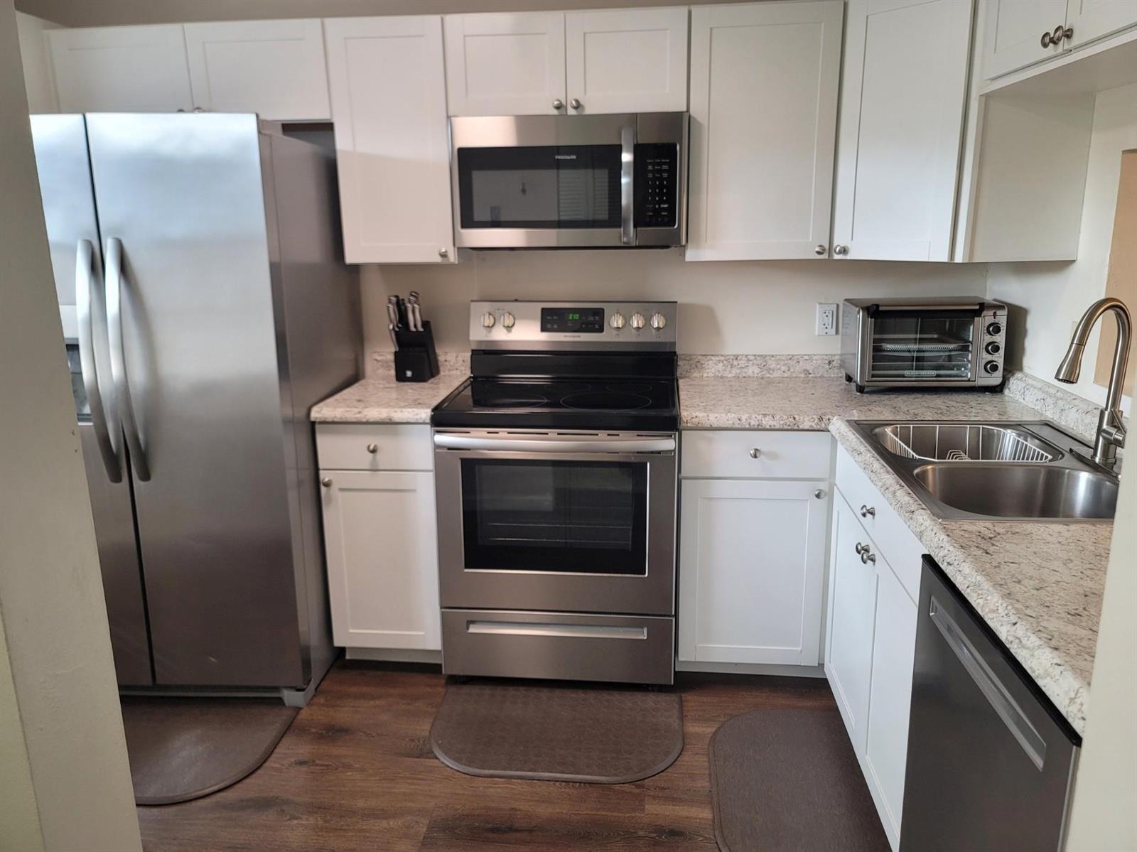 A kitchen features white cabinets, stainless steel appliances, and speckled granite countertops — 3774 Inverrary Boulevard # P202, Lauderhill FL 33319, LAUDERHILL, FL