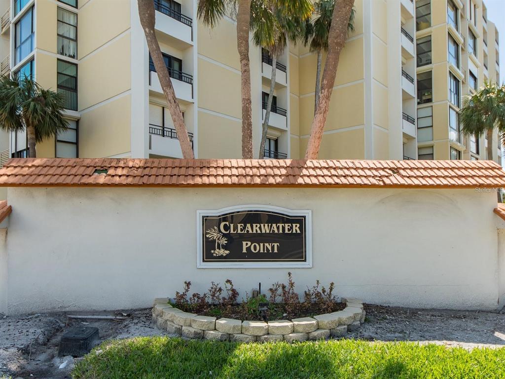 A beige stucco wall with a Clearwater Point sign stands before a tall apartment building — 800 S GULFVIEW BOULEVARD UNIT 305, CLEARWATER BEACH, FL