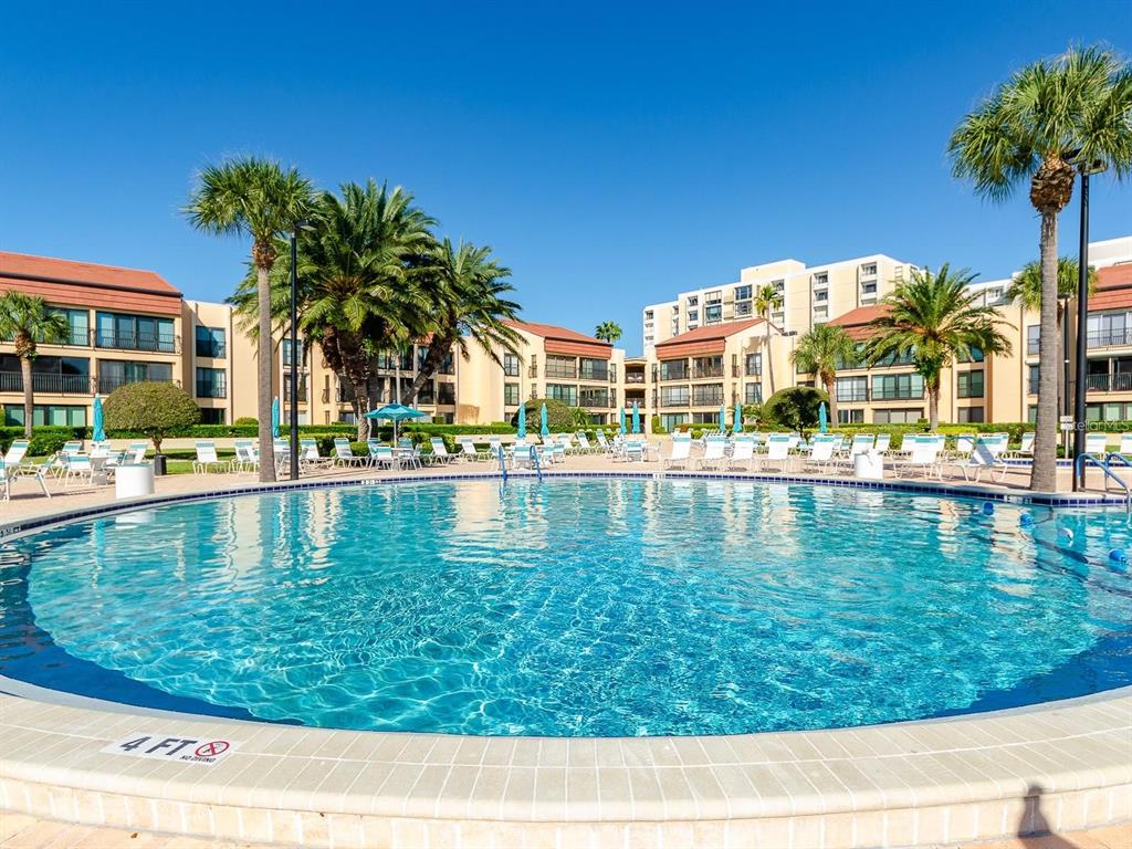A swimming pool with a four-foot depth marker sits in front of a multi-story resort — 800 S GULFVIEW BOULEVARD UNIT 305, CLEARWATER BEACH, FL