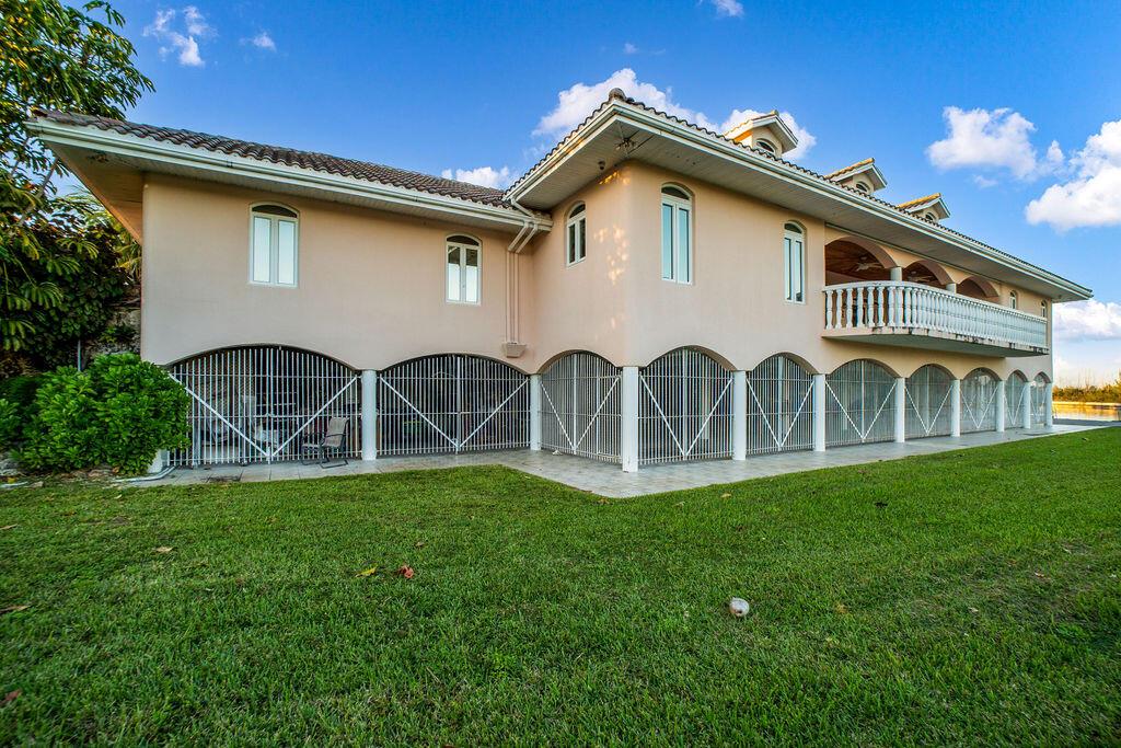 A two-story house with a beige exterior, arched ground-level security gates, and a balcony — 42 Dunton Lane, FL