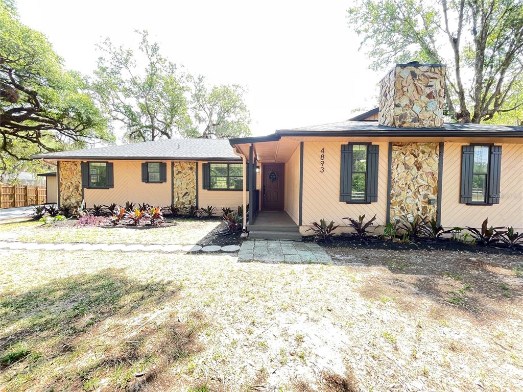 A single-story house with peach siding, stone accents, and a dark shingled roof — 4893 S OLD FLORAL CITY ROAD, INVERNESS, FL
