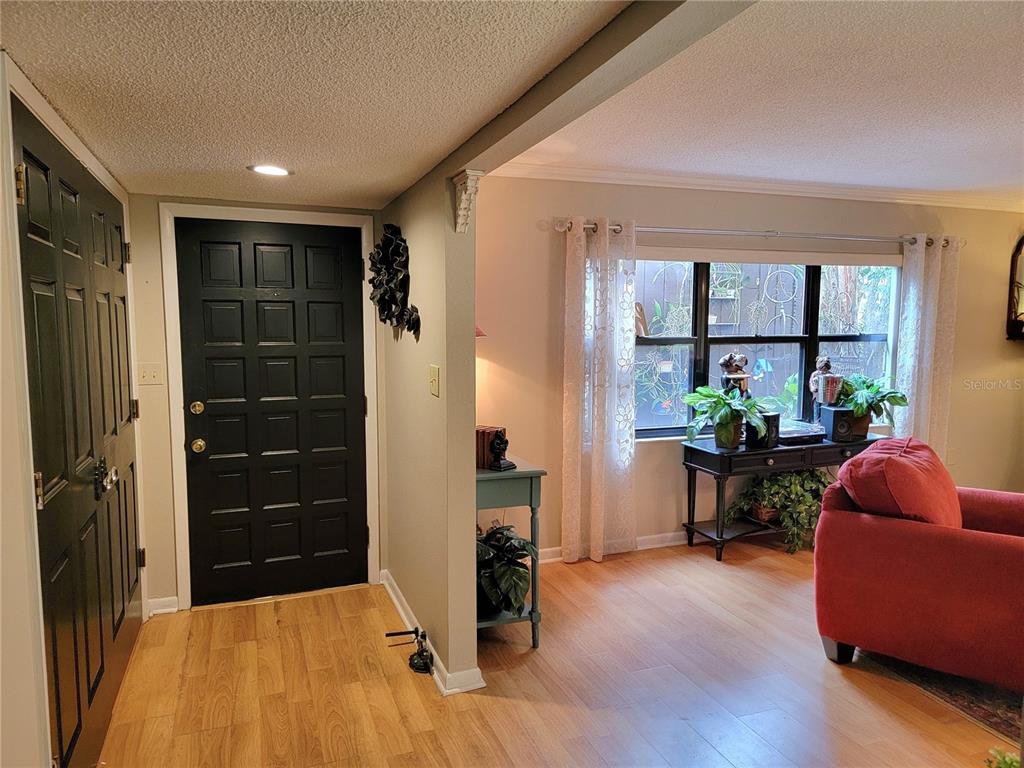 An entryway with a black door and wood-look flooring leads into a living area — 1 CASA LOMA WAY, LAKELAND, FL