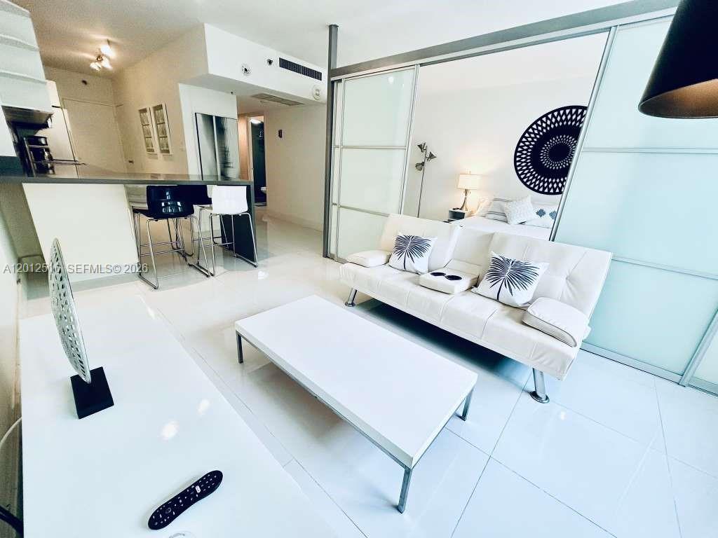A modern living room features a white sofa, a coffee table, and a mirrored wall — 100 Lincoln Rd # 526, Miami Beach FL 33139, MIAMI BEACH, FL
