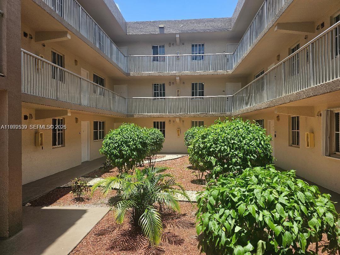 An open-air courtyard with a central garden is surrounded by a multi-story apartment building — 6155 NW 186th St # 207, Hialeah FL 33015, HIALEAH, FL