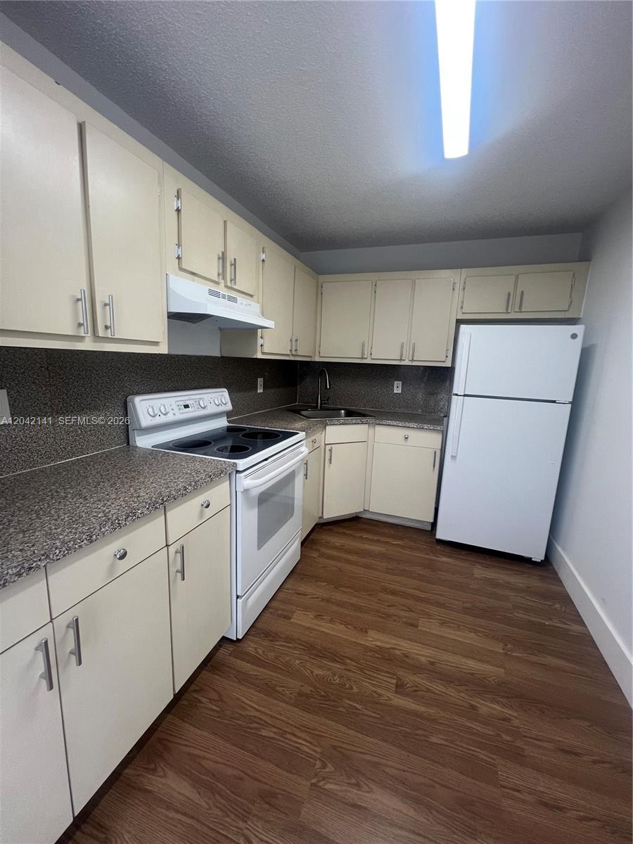 A kitchen features light-colored cabinets, a white stove, a white refrigerator, and speckled countertops — 6141 W 22nd Ct # 202, Hialeah FL 33016, HIALEAH, FL