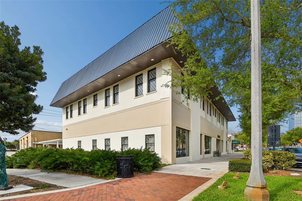 A two-story commercial building with a dark metal roof and light-colored stucco exterior — 201 W 1ST STREET, SANFORD, FL