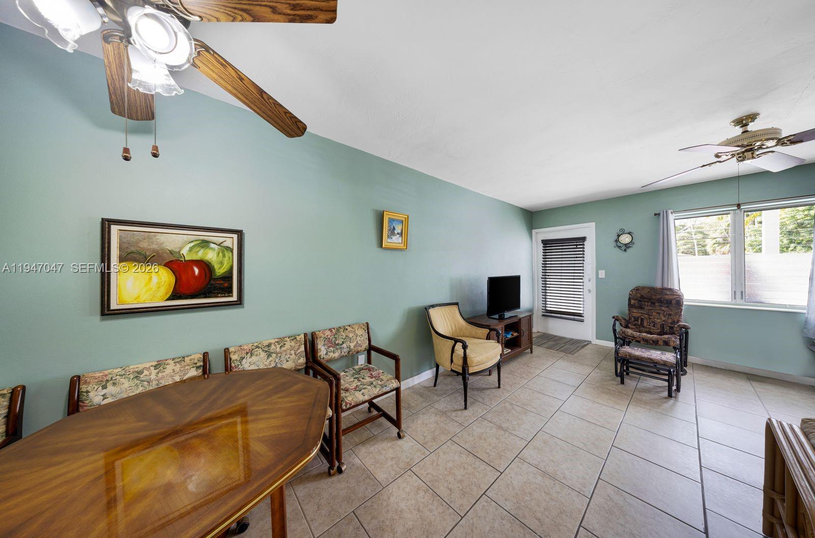 A dining area with a wooden table, floral chairs, light green walls, and tiled floors — 15610 NE 6th Ave # 7D, Miami FL 33162, MIAMI, FL