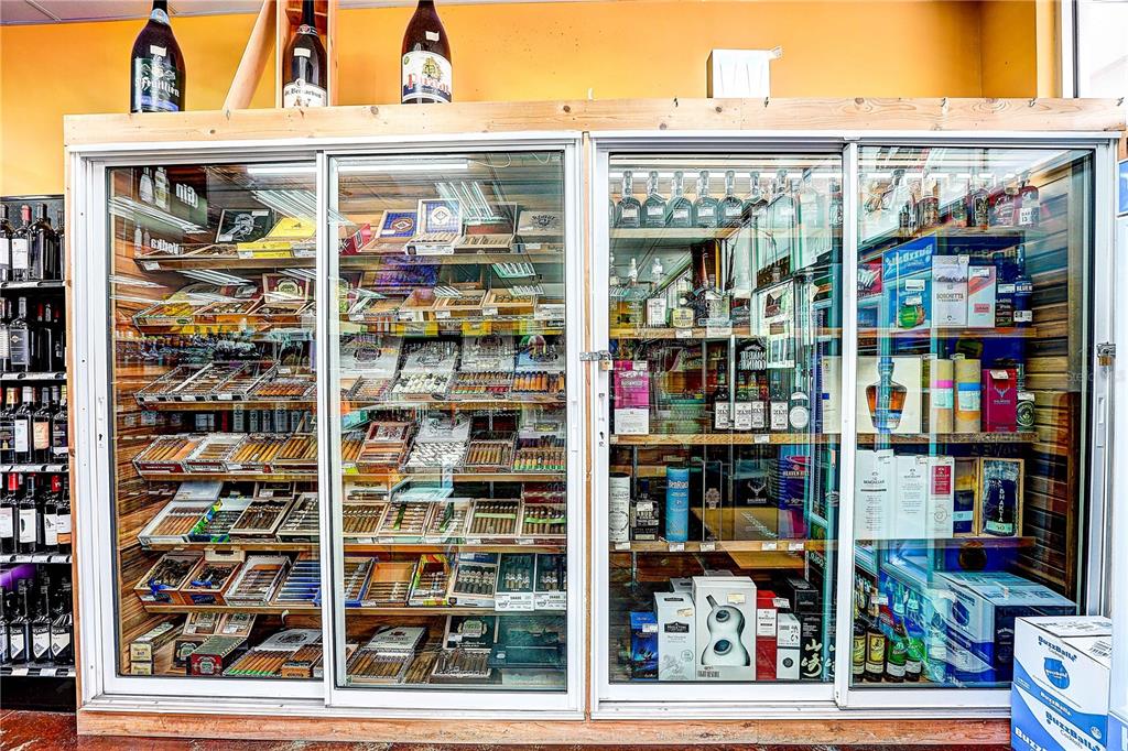 A liquor store display case features shelves stocked with various cigars and bottled spirits — COLLIER PARKWAY, LAND O LAKES, FL