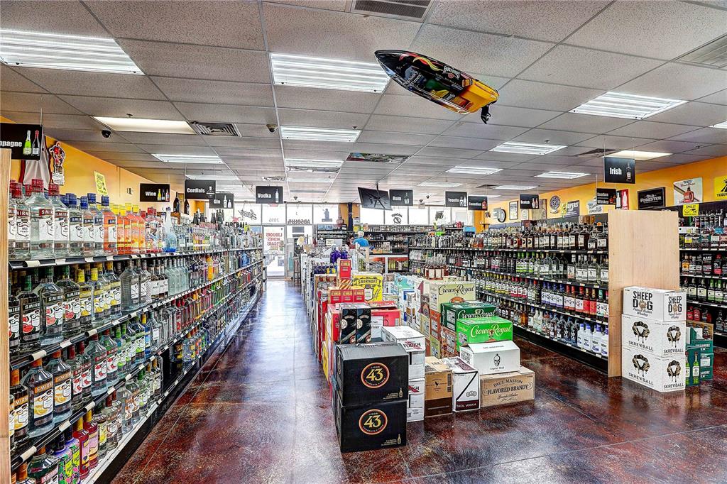 A liquor store interior features long aisles of stocked shelves and a suspended model boat — COLLIER PARKWAY, LAND O LAKES, FL