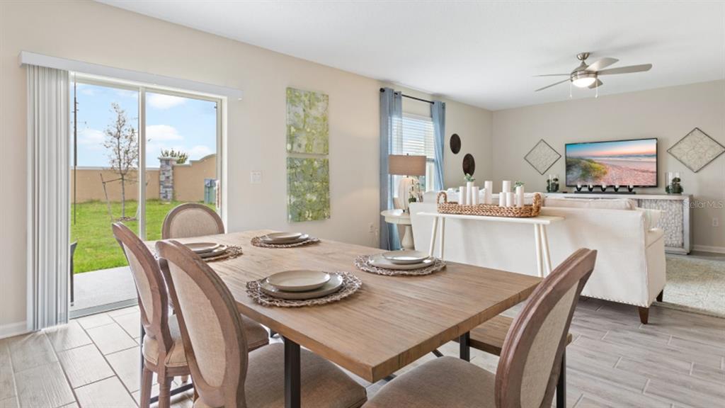 A dining area with a wooden table and chairs overlooks a backyard through sliding doors — 5234 WORCHESTER DRIVE, KISSIMMEE, FL