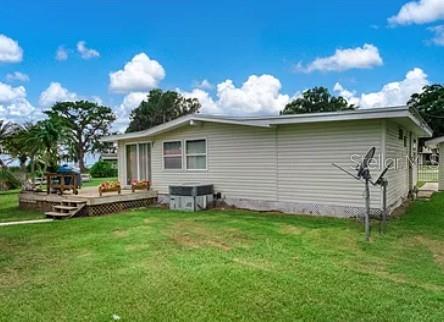 A light-colored mobile home features a wooden deck and a satellite dish in the yard — 221 SPECKLED PERCH POINT, LORIDA, FL
