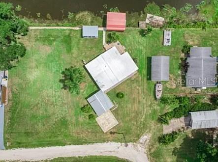 An aerial view shows a house with several outbuildings on a large, grassy waterfront lot — 221 SPECKLED PERCH POINT, LORIDA, FL