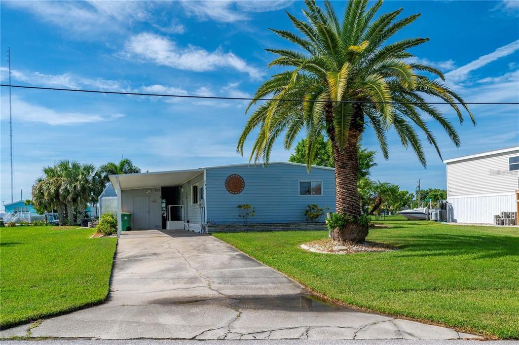 A light blue mobile home with a concrete driveway and a large palm tree — 731 TANGERINE COURT, PUNTA GORDA, FL