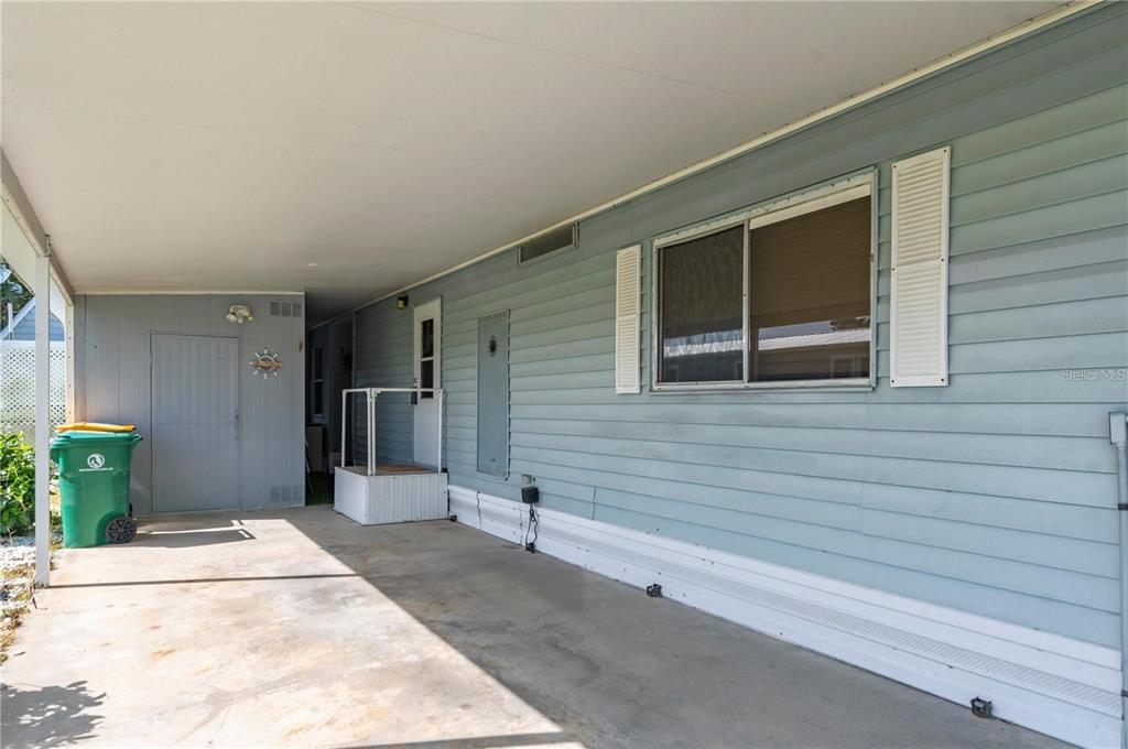 A covered concrete carport sits beside the light blue siding of a mobile home — 731 TANGERINE COURT, PUNTA GORDA, FL