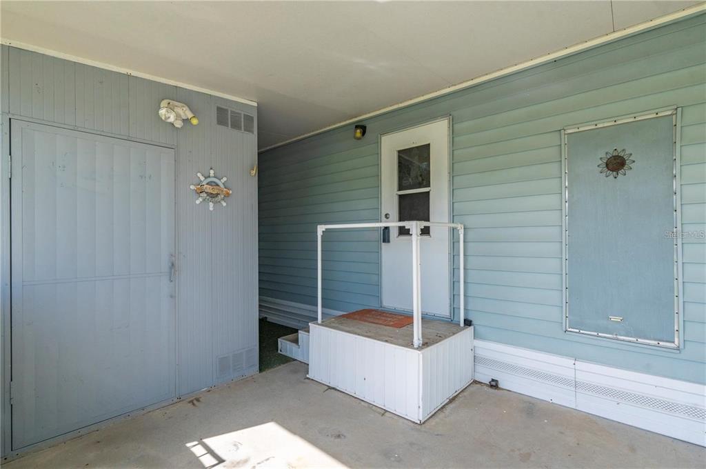 A covered concrete porch features a small wooden entry platform with a white metal railing — 731 TANGERINE COURT, PUNTA GORDA, FL