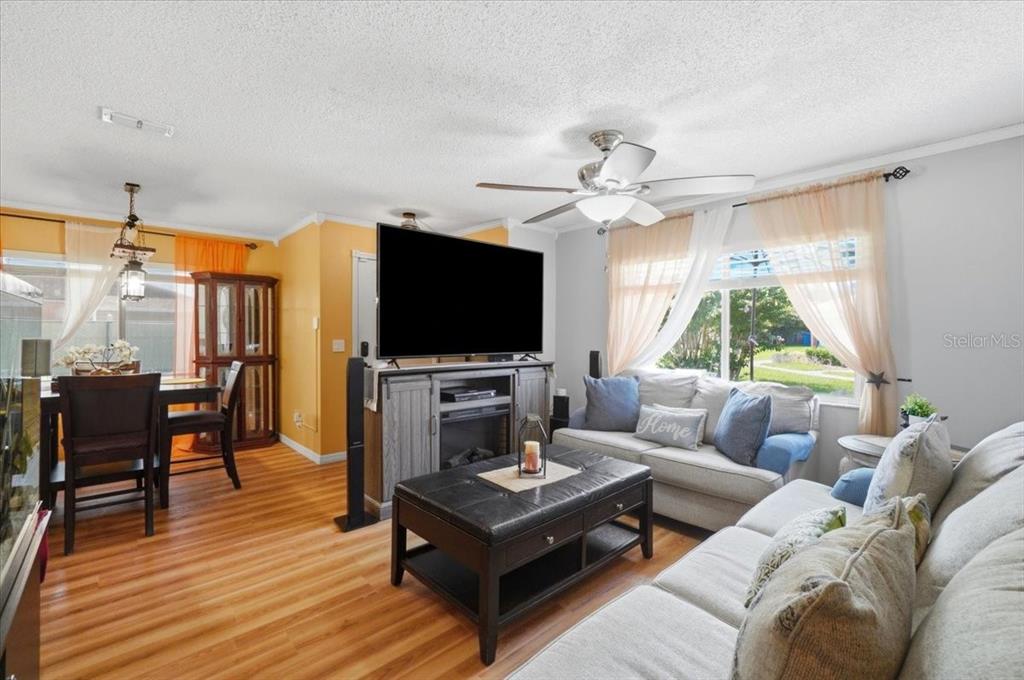 A living room features a television on a media console, a sofa, and dining area — 7902 WATERVIEW WAY, WINTER HAVEN, FL