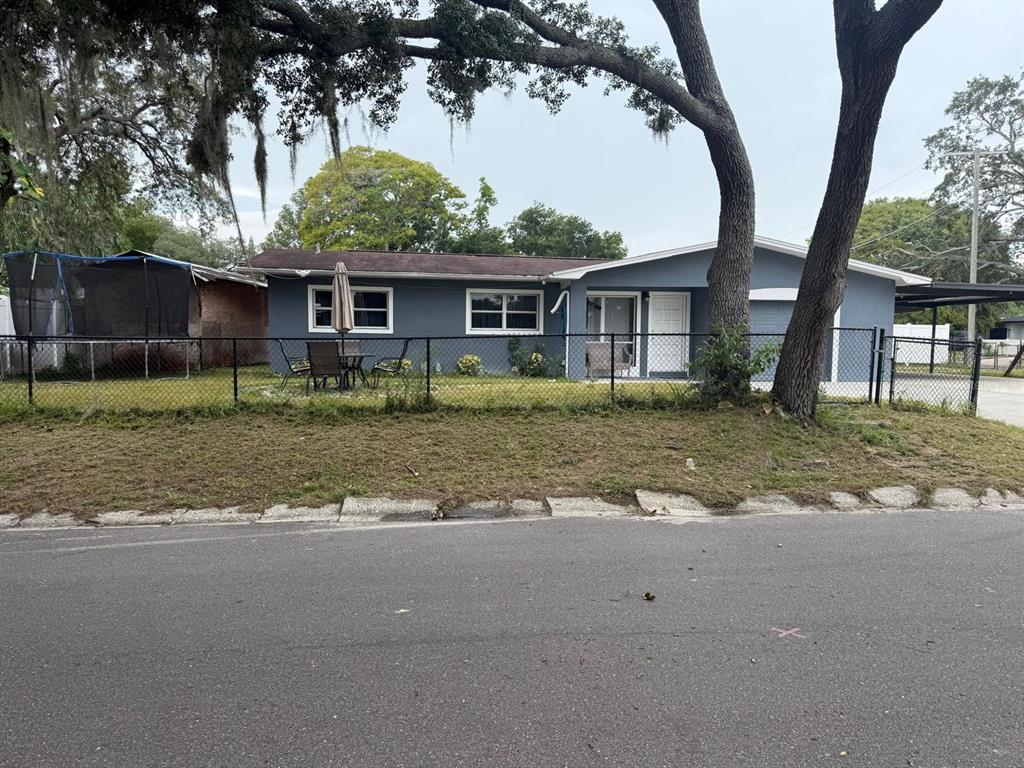 A single-story blue house with a chain-link fence and a large tree in the yard — 1827 HEATHER AVENUE, TAMPA, FL