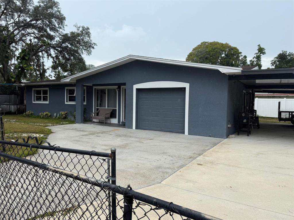 A dark gray house features a single-car garage, a concrete driveway, and a covered carport — 1827 HEATHER AVENUE, TAMPA, FL