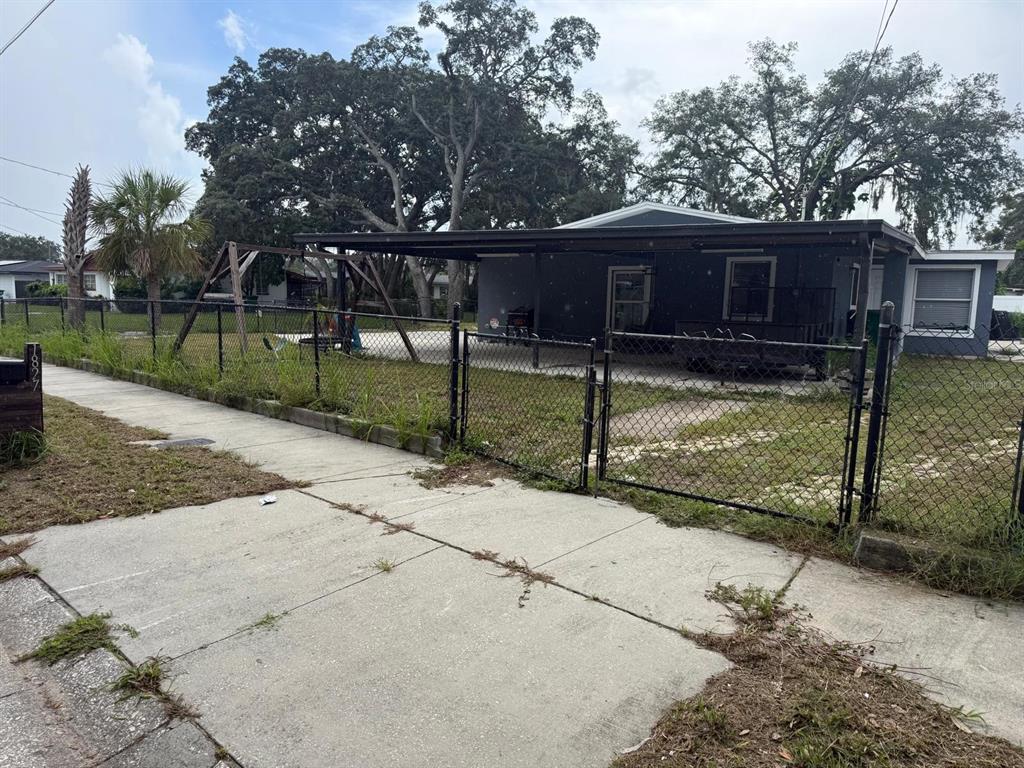 A single-story house with a carport and a chain-link fence in the front yard — 1827 HEATHER AVENUE, TAMPA, FL