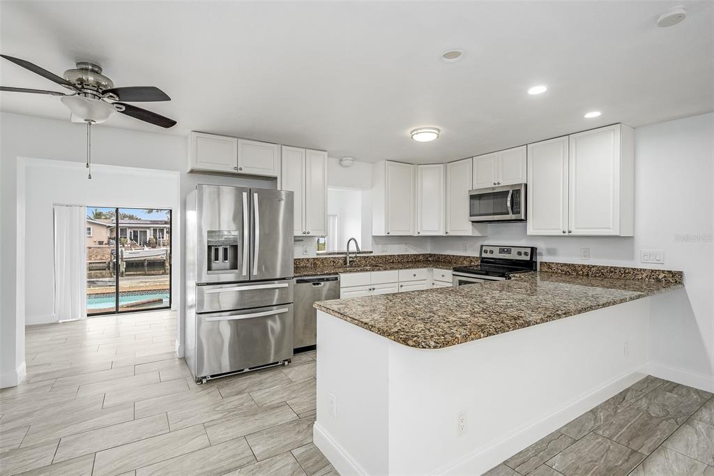 A kitchen with white cabinets, granite countertops, stainless steel appliances, and tile flooring — 1730 E RIVIERA DRIVE, MERRITT ISLAND, FL