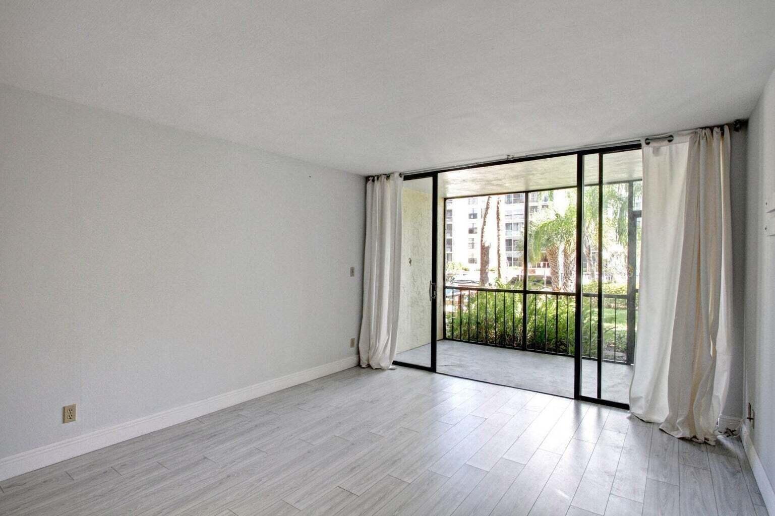 An empty room with light wood-look flooring and a sliding glass door leading to a balcony — 11 Royal Palm Way # 1040, Boca Raton FL 33432, BOCA RATON, FL