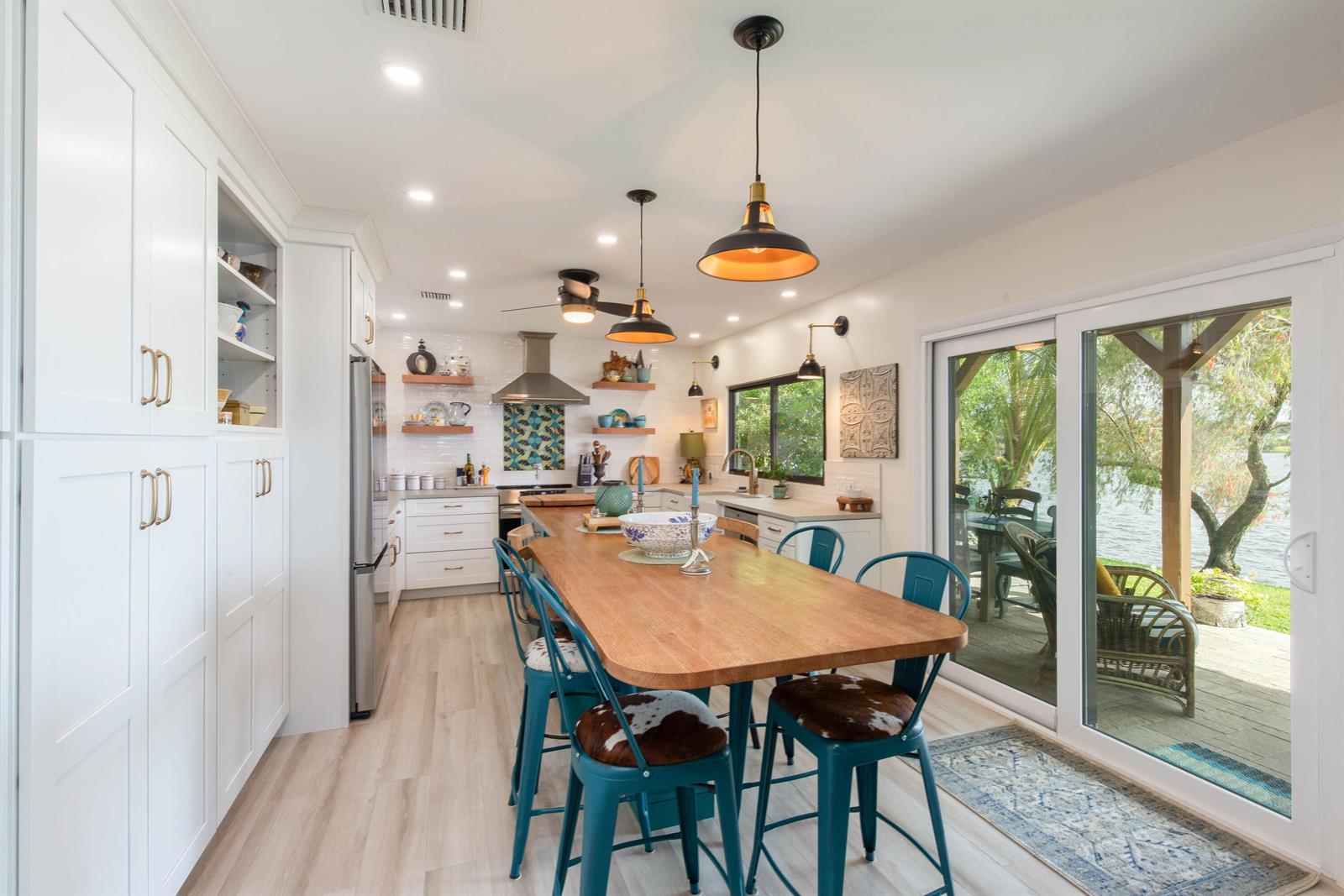 A kitchen features a wooden island with teal stools, white cabinetry, and sliding glass doors — 1734 Harborside Circle, Wellington FL 33414, WELLINGTON, FL