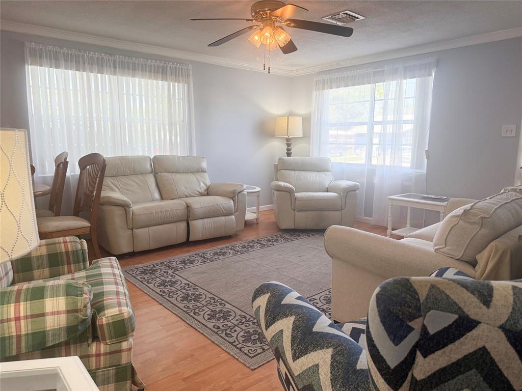 A living room features light-colored furniture, a patterned area rug, and wood-look flooring — 13157 CLAY AVENUE, LARGO, FL