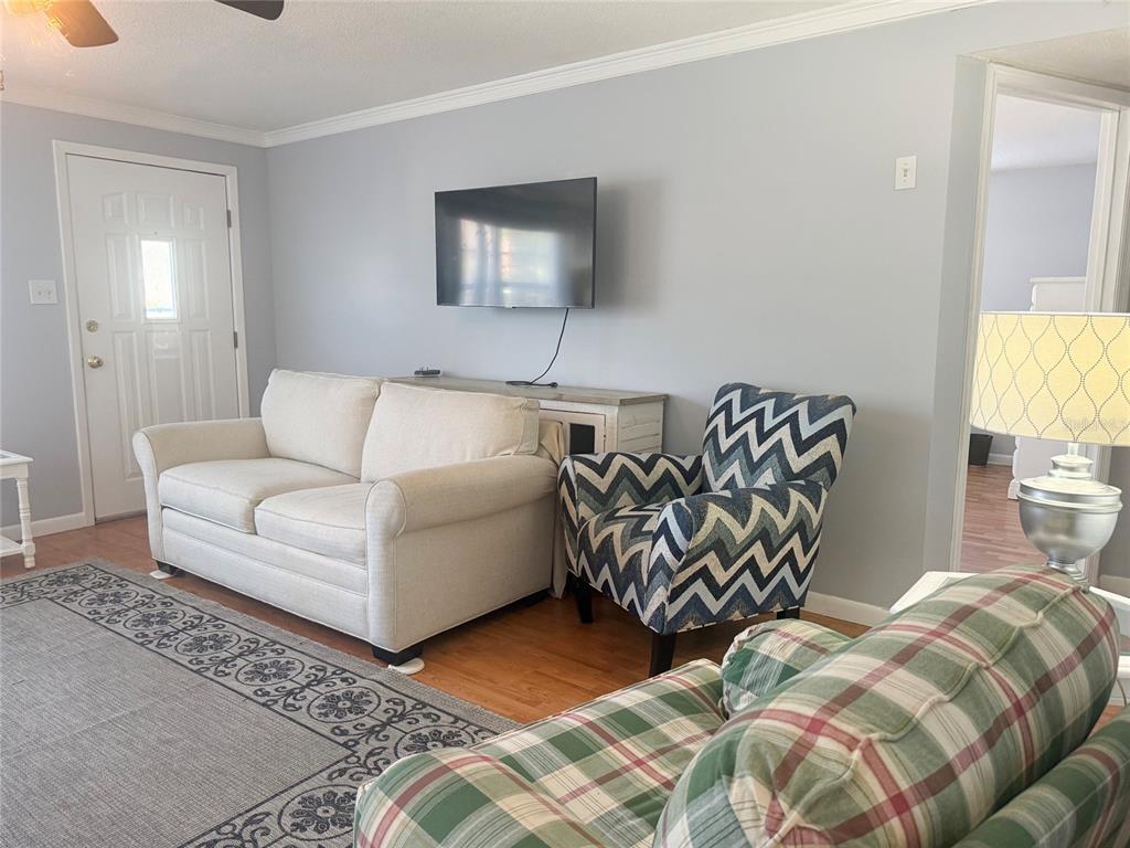 A living room features a white sofa, a chevron-patterned armchair, and a wall-mounted television — 13157 CLAY AVENUE, LARGO, FL