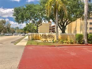 The exterior of the Mirassou condominium complex features a yellow sign and palm trees — 6045 NW 186th St # 116, Hialeah FL 33015, HIALEAH, FL