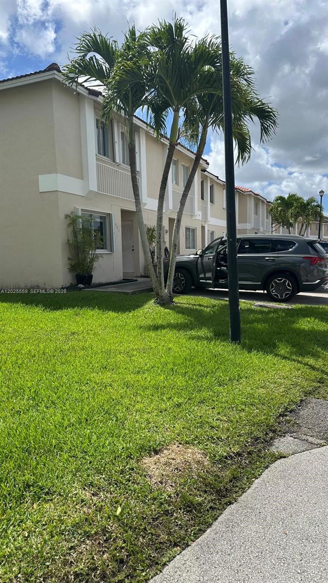 A two-story townhouse exterior features a palm tree, a green lawn, and a parked SUV — MIAMI, FL