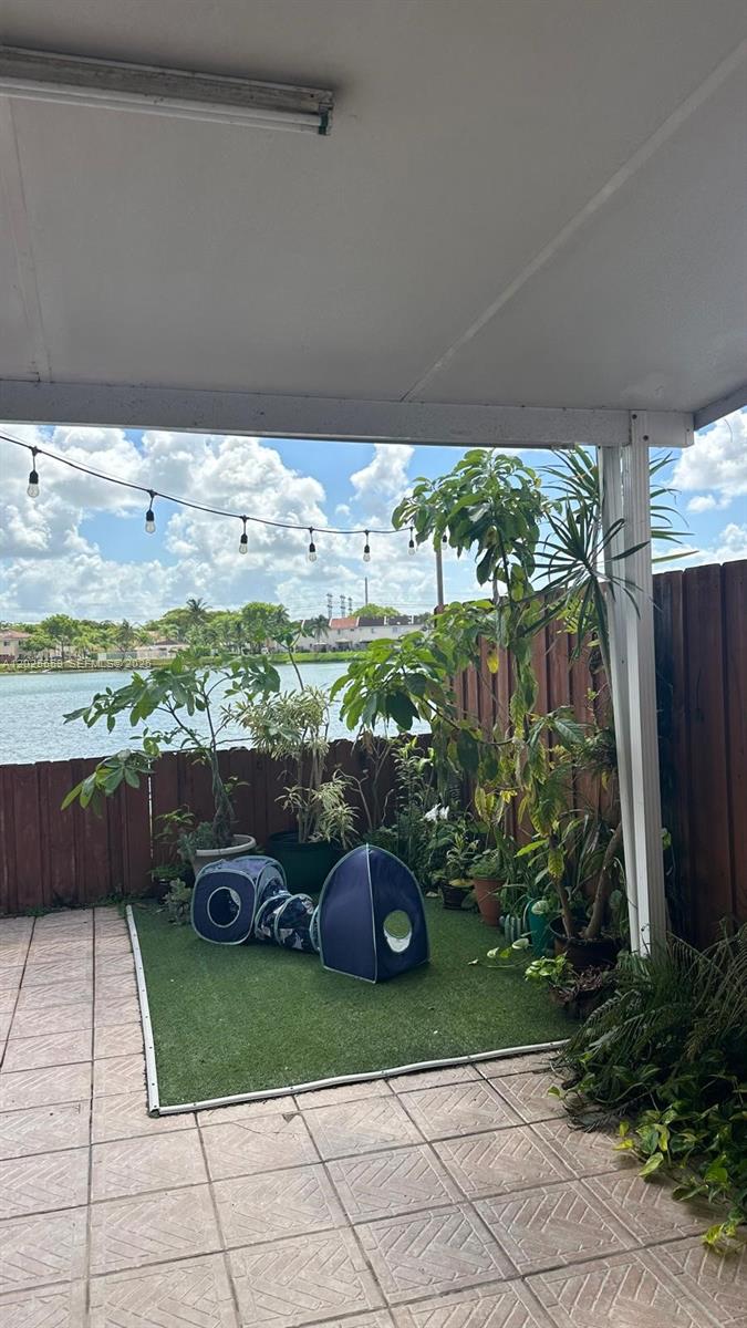 A covered patio features tiled flooring, an artificial turf area with potted plants, and a lake view — MIAMI, FL