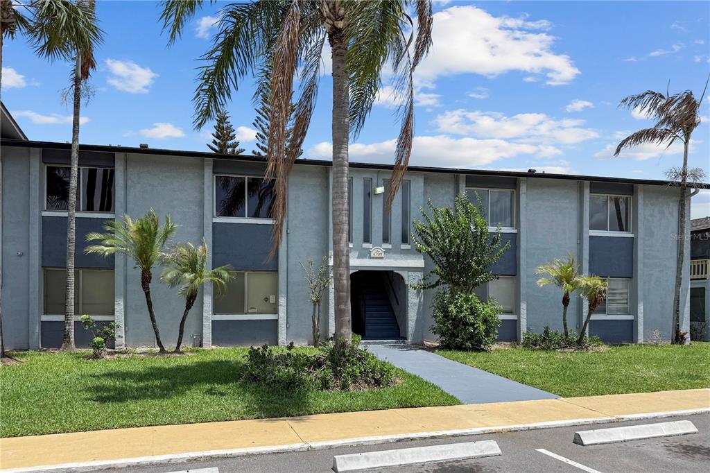A two-story apartment building with gray stucco walls, palm trees, and a central entryway — 4709 S TEXAS AVENUE UNIT 4709D, ORLANDO, FL