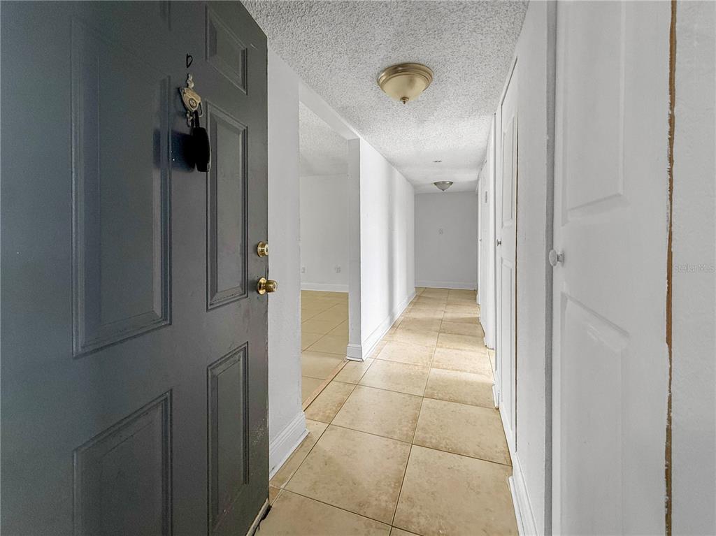 An entryway with a dark door, tiled floor, and a hallway leading to another room — 4709 S TEXAS AVENUE UNIT 4709D, ORLANDO, FL
