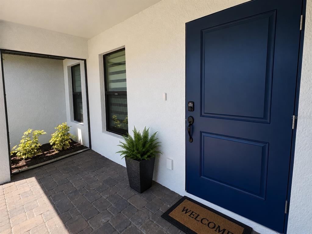 A dark blue front door opens onto a paved porch with a potted fern — 93 PRESQUE ISLE DRIVE, PORT CHARLOTTE, FL