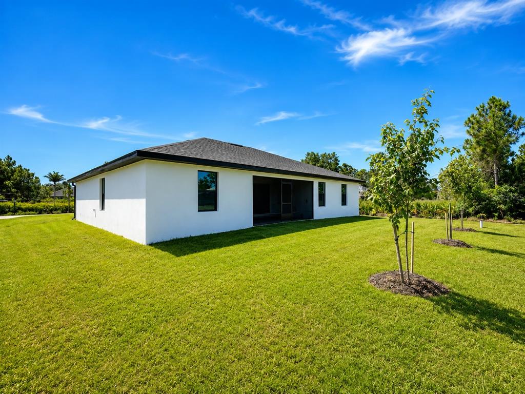 The exterior of a white house with a dark roof sits on a grassy lawn — 93 PRESQUE ISLE DRIVE, PORT CHARLOTTE, FL
