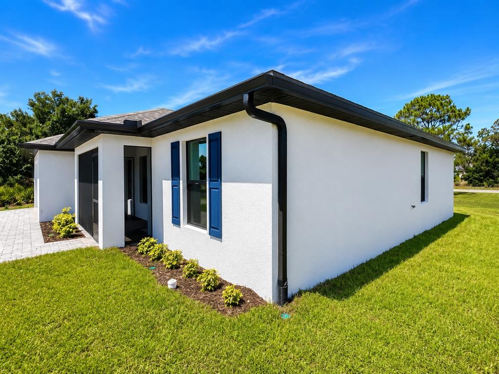 The exterior of a white stucco house features a black gutter system and blue shutters — 93 PRESQUE ISLE DRIVE, PORT CHARLOTTE, FL