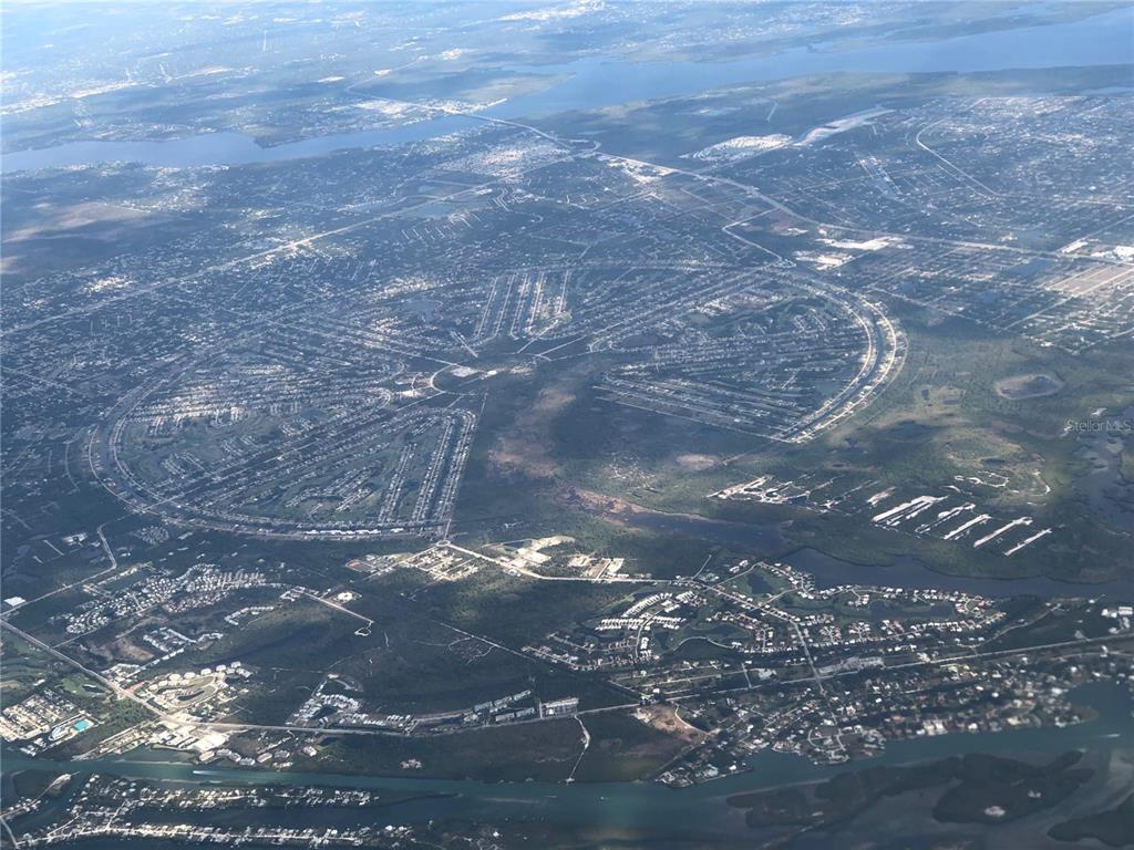 An aerial view of a large circular residential development surrounded by water and natural land — 1162 BOUNDARY BOULEVARD, ROTONDA WEST, FL