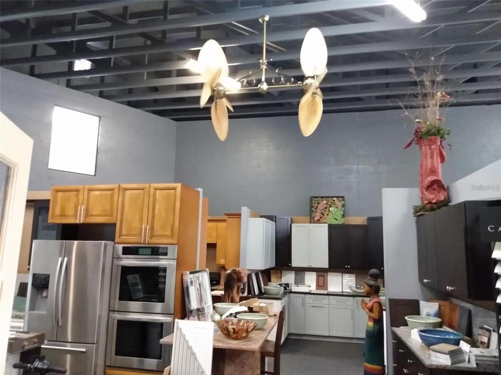 A kitchen showroom features various cabinet styles, stainless steel appliances, and a unique dual-fan fixture — 10120 RIDGEWAY DRIVE, PORT RICHEY, FL