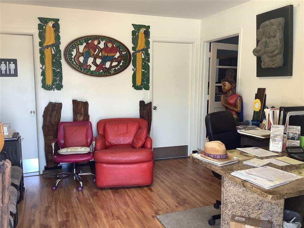 An office space features red seating, parrot wall art, a desk, and a decorative statue — 10120 RIDGEWAY DRIVE, PORT RICHEY, FL