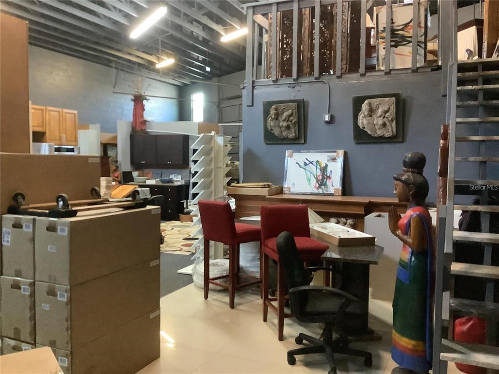 A warehouse-style room features cardboard boxes, red bar stools, a desk, and decorative wall art — 10120 RIDGEWAY DRIVE, PORT RICHEY, FL