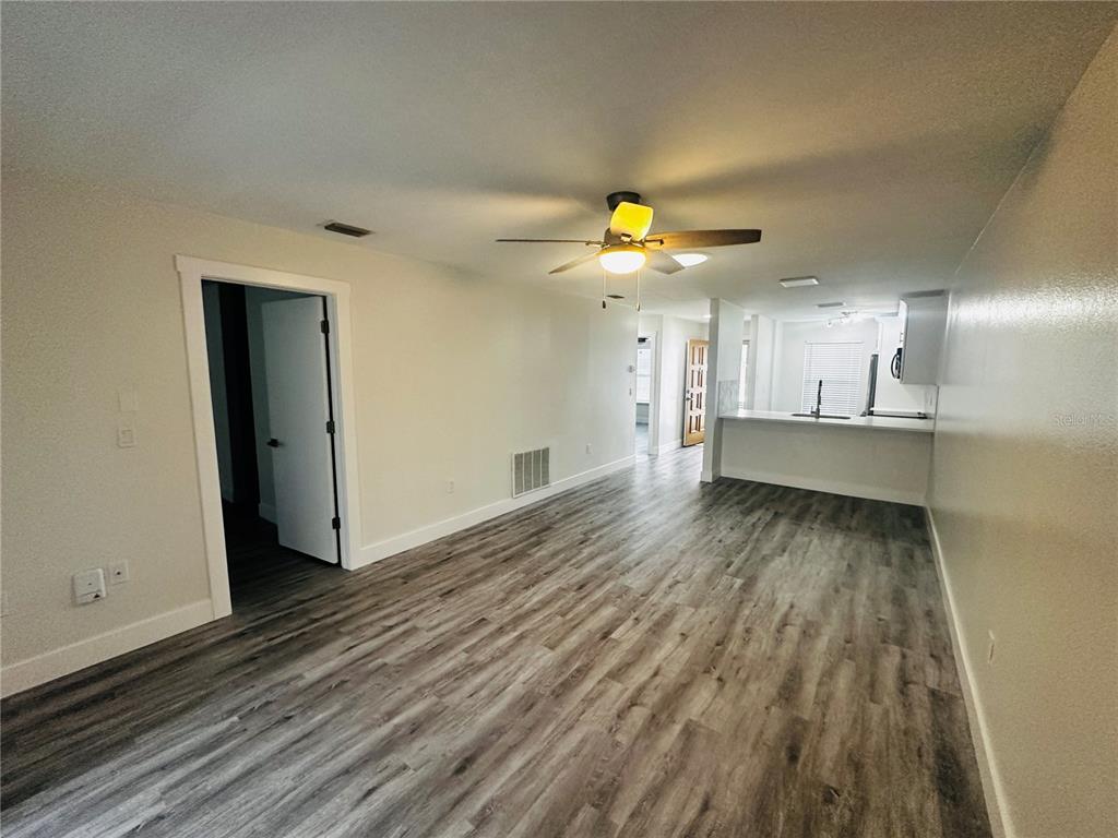 An open-concept living area features light-colored walls, wood-look flooring, and a kitchen with a breakfast bar — 3005 WAINWRIGHT COURT, NEW PORT RICHEY, FL
