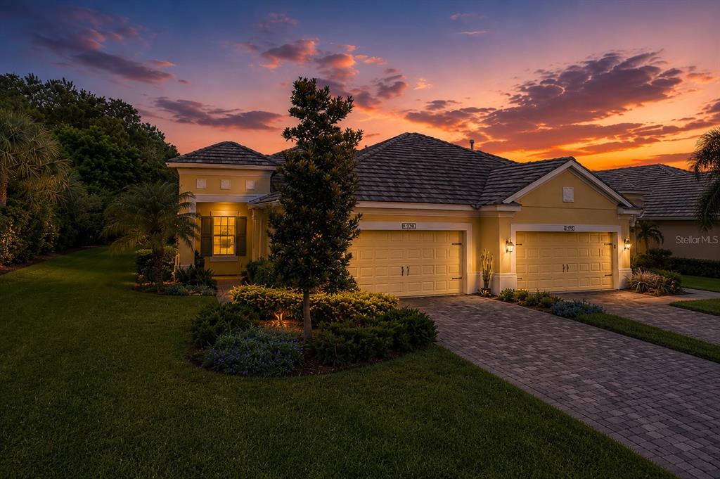 A single-story house with a paved driveway and two-car garage at sunset — 1936 ORANGE LAKE COVE, BRADENTON, FL