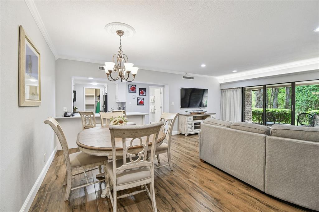A dining area with a round wooden table sits adjacent to a living room — 36750 US HIGHWAY 19 N UNIT 03116, PALM HARBOR, FL