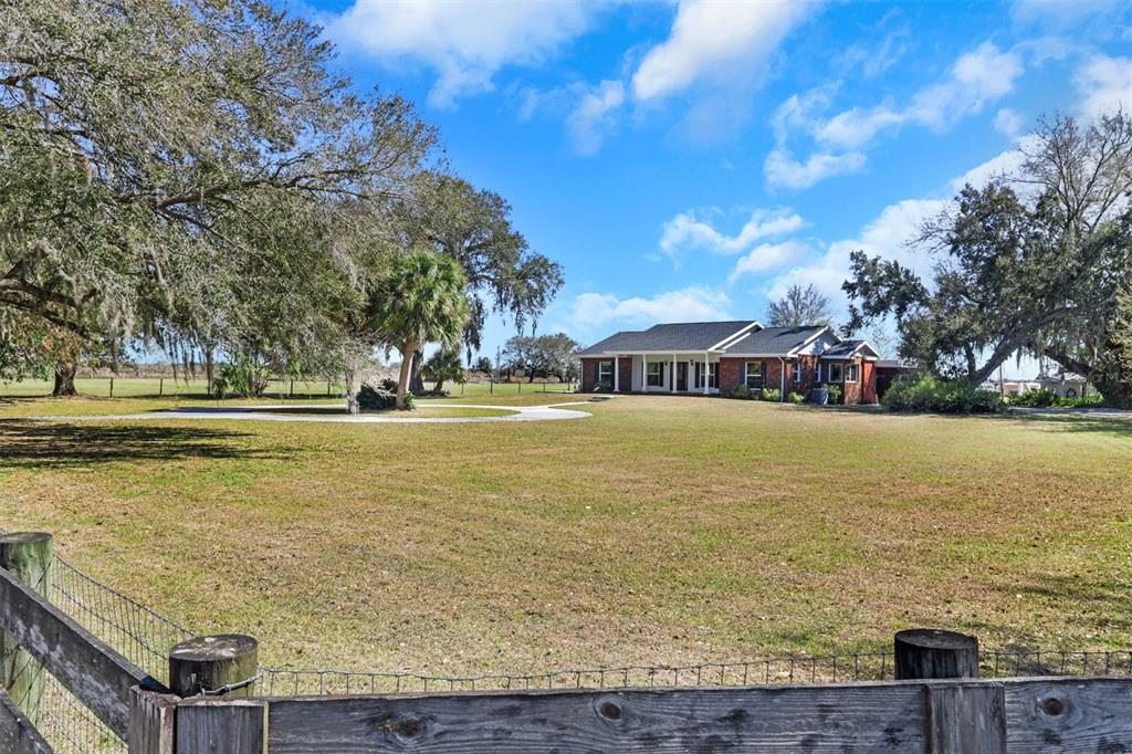 A single-story brick house sits on a large, grassy lot with mature trees — 3597 SE CO RD 760 ROAD UNIT 760, ARCADIA, FL